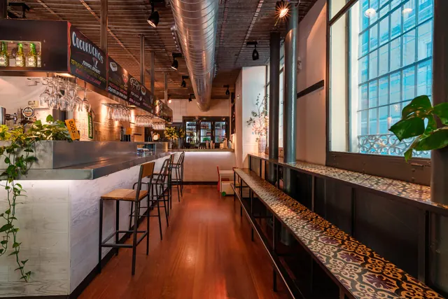 Interior de un restaurante con luz natural y mesas junto a la ventana